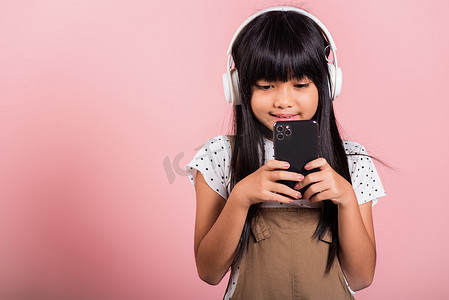 亚洲孩子 10 岁享受手机听音乐佩戴无线耳机