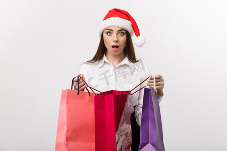 强迫症摄影照片_圣诞节概念-美丽的白种人女商人震惊与购物袋内的礼物。