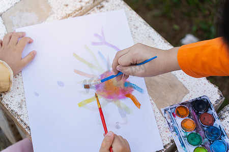 可爱的小孩用彩色颜料画画。