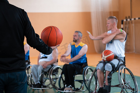 残疾篮球队选拔员站在球员面前，向他们展示训练开始前的伸展运动