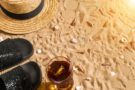 里字摄影照片_夏季沙滩装、人字拖、帽子、玻璃杯里的冷饮和沙滩上的贝壳。