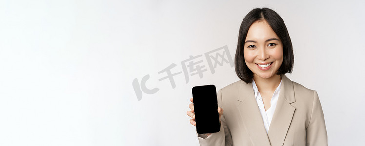 显示智能手机应用程序界面、手机屏幕、站在白色背景上的亚洲企业女性肖像