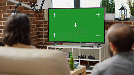 男人和女人在电视显示屏上观看绿屏