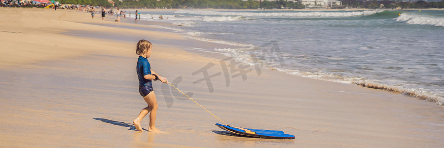快乐的小男孩在度假时在海滩上玩得开心，带着布吉板横幅，长格式
