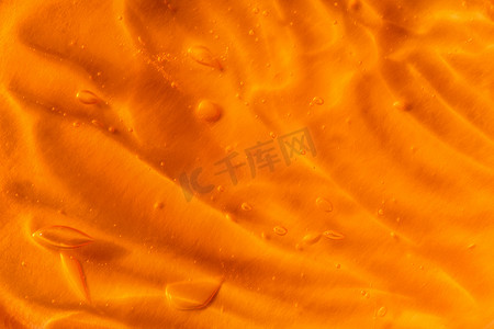 橙色背景上带有气泡和波浪的透明黄色凝胶的纹理