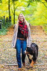遛狗的女人摄影照片_在公园里用皮带遛狗的女人