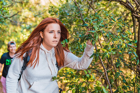 年轻的红发女子在大自然中行走，凝视着地平线。