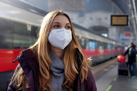 火车站背景上戴着 KN95 FFP2 医用口罩的女孩肖像，背景是移动的火车。