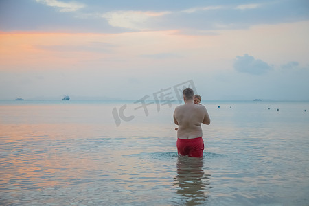 父亲手里拿着小孩进入海水后视图。
