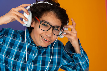 十几岁的男孩戴着耳机听音乐紫色背景