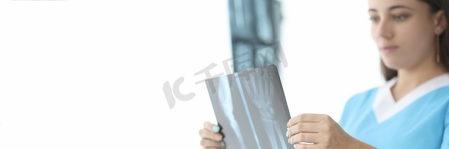 手部x光片摄影照片_创伤科医生在诊所特写中观察手部 X 光片