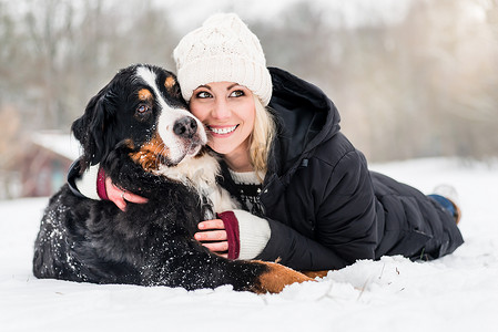 在雪地里拥抱她的狗的女人