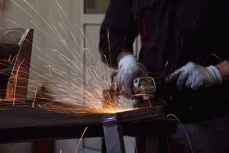 重工业工程工厂内部与产业工人使用角磨机和切割金属管。