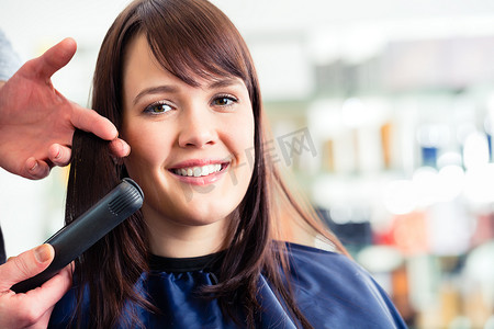扁平女扁平摄影照片_男理发师在店里用扁铁给女头发做造型