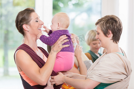 年轻女性学习如何使用婴儿背带来抱孩子