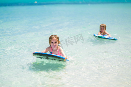 双胞胎兄妹在海里享受冲浪的乐趣。