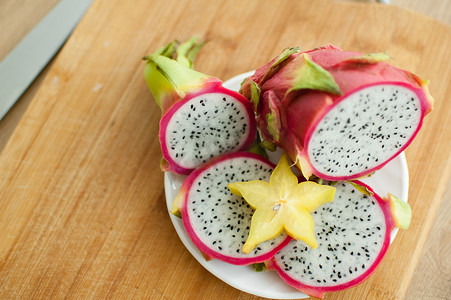 火龙果或火龙果片，白色果肉和黑色种子，放在白盘上，配上一片杨桃或杨桃。