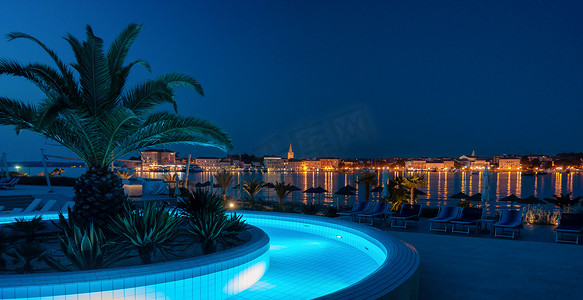 克罗地亚波雷奇晚上，前面有灯光的游泳池