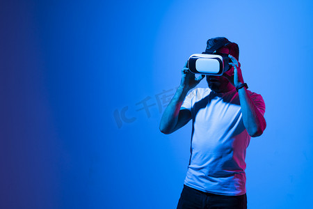戴着 VR 眼镜、留着胡子的严肃男子在元宇宙中与朋友玩游戏，并试图在霓虹灯下触摸某些东西。