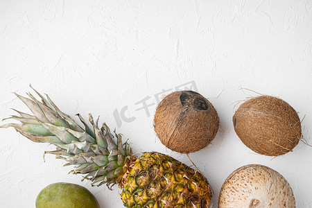 由异国情调和热带水果、菠萝和椰子制成的创意布局，白色石桌背景，顶视图平躺，带有文本复制空间