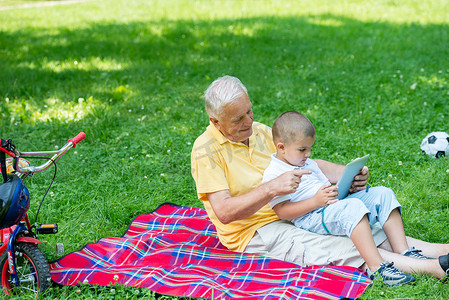 祖父和孩子在公园里使用平板电脑