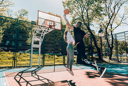 打篮球的的人摄影照片_戴着假肢的年轻人和朋友在球场上打篮球