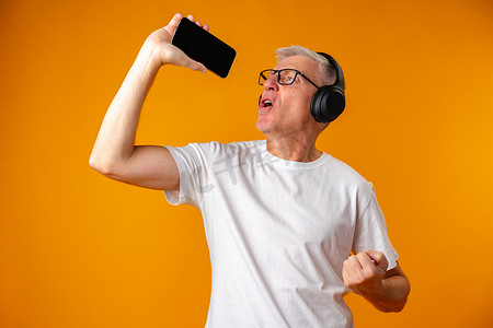 老人用耳机听音乐，手持智能手机，如麦克风