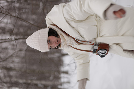 冬天在树林里散步时带着相机的女孩