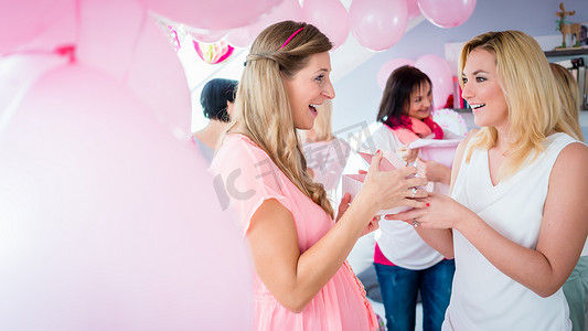 朋友送礼摄影照片_女人在迎婴派对上给怀孕的朋友送礼物