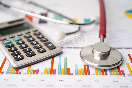 图表或方格纸上的听诊器和计算器、财务、账户、统计和商业数据医疗健康概念。