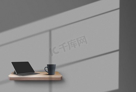 木架上立着一块平板电脑和一个杯子，悬挂在灰色的墙壁上，窗户的阴影投射在上面。