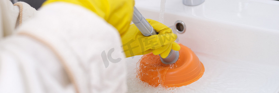 戴黄色手套的人正在清理水槽中的堵塞特写