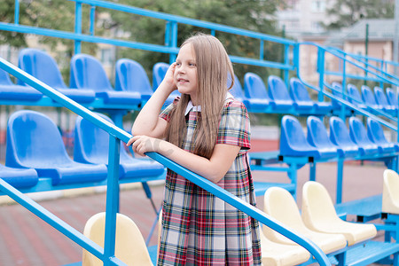 穿着校服的漂亮女孩在学校体育场的蓝色和黄色论坛上。