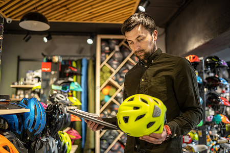 自行车店经理在平板电脑上检查头盔价格信息，卖家在体育商店盘点库存。