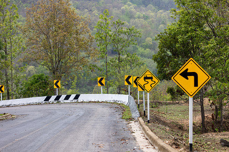 指示图标摄影照片_指示左转和山路湿滑危险的路标警告