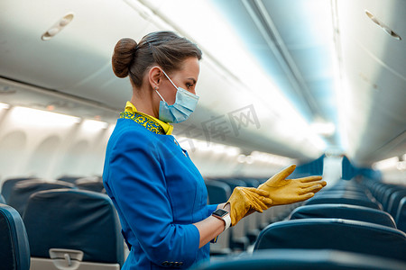 戴医用口罩的空姐在飞机上戴上手套