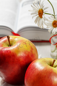 两个大红苹果在背景上打开了书