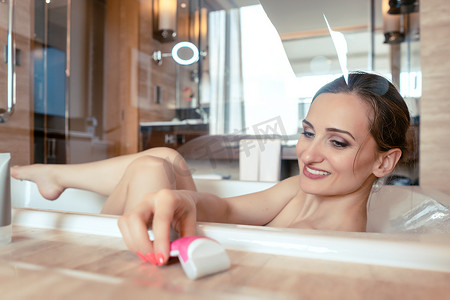 在酒店浴缸里洗澡的女人抓起剃须刀