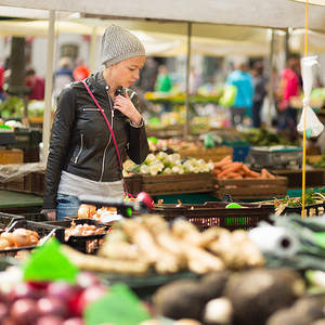 水果商店摄影照片_妇女在当地食品市场购买蔬菜。