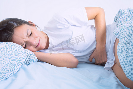 躺在床上的妇女患有月经痛、胃痛或腹痛。