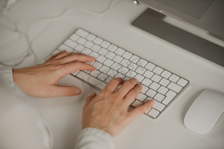 一体机电脑摄影照片_女性双手在无线白色铝制键盘上打字的特写照片。