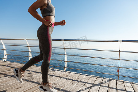 女性沿着海边跑步、慢跑和在海边锻炼的裁剪镜头