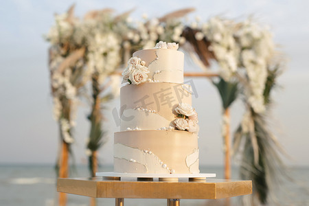 海滩婚礼上的婚礼蛋糕，背景是美丽的拱门，用于退出仪式