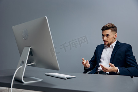 坐在电脑前办公桌前的商人灰色背景