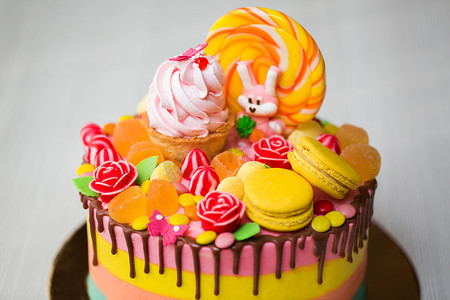 适合儿童生日派对的彩色蛋糕，配有棒棒糖、糖果、果酱、纸杯蛋糕和兔子。