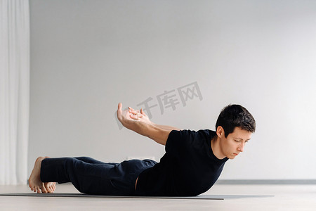 一名身穿黑色T恤的男子躺在健身房里做伸展运动