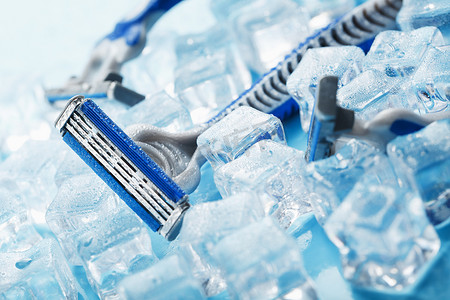 三台剃须机在冷淡的蓝色背景上加冰。