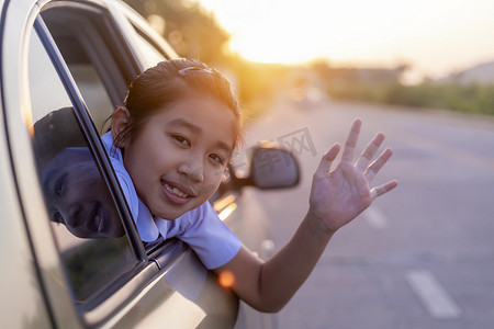 上学的路上，小女孩从车窗里伸出了手，笑着说。