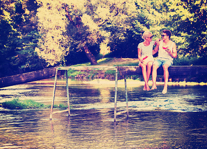 一对夫妇坐在木桥上享用西瓜