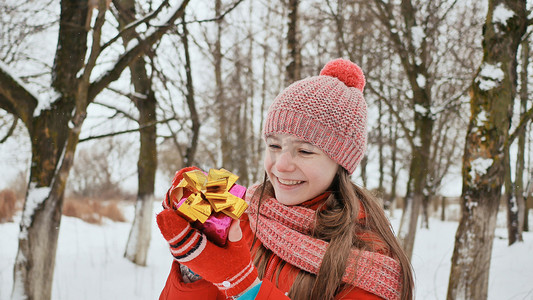 冬天，一位美丽的年轻女学生站在白雪皑皑的森林里，从朋友手中接过一份快乐的礼物。